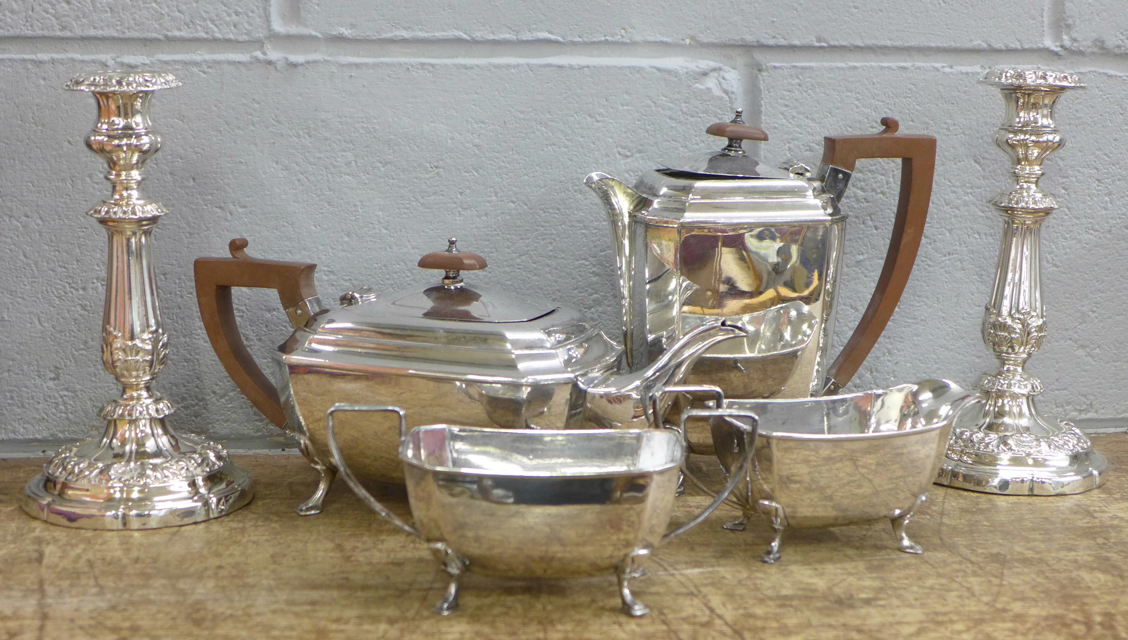 A pair of plated candlesticks and a four piece plated tea service