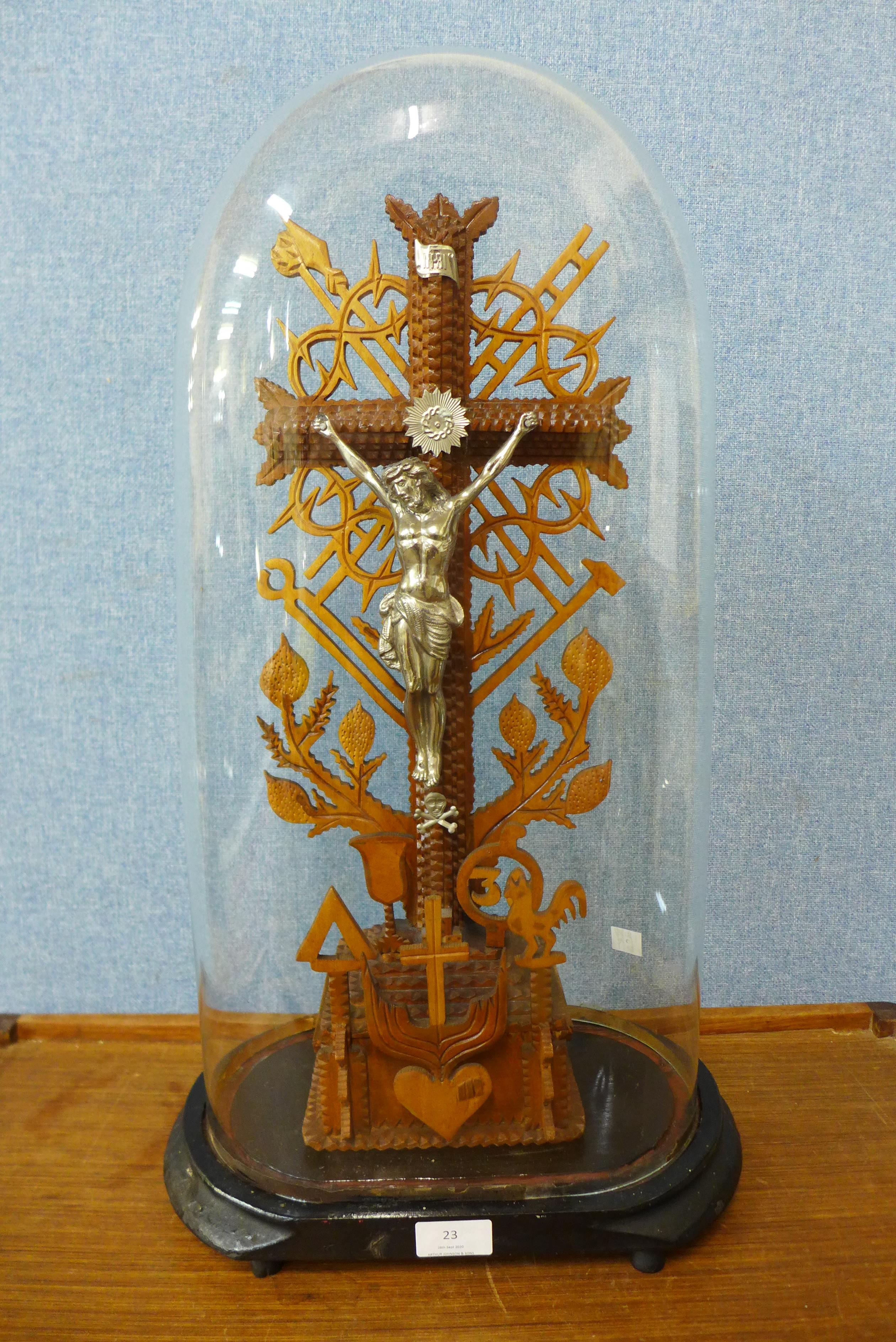 A Tramp Art carved wood crucifix, in glass dome and on ebonised base