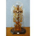 A Tramp Art carved wood crucifix, in glass dome and on ebonised base