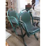 A set of four green metal stacking chairs