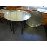 An Eastern brass topped folding table and another brass top