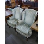 A pair of 1930's Queen Anne style walnut and upholstered wingback armchairs