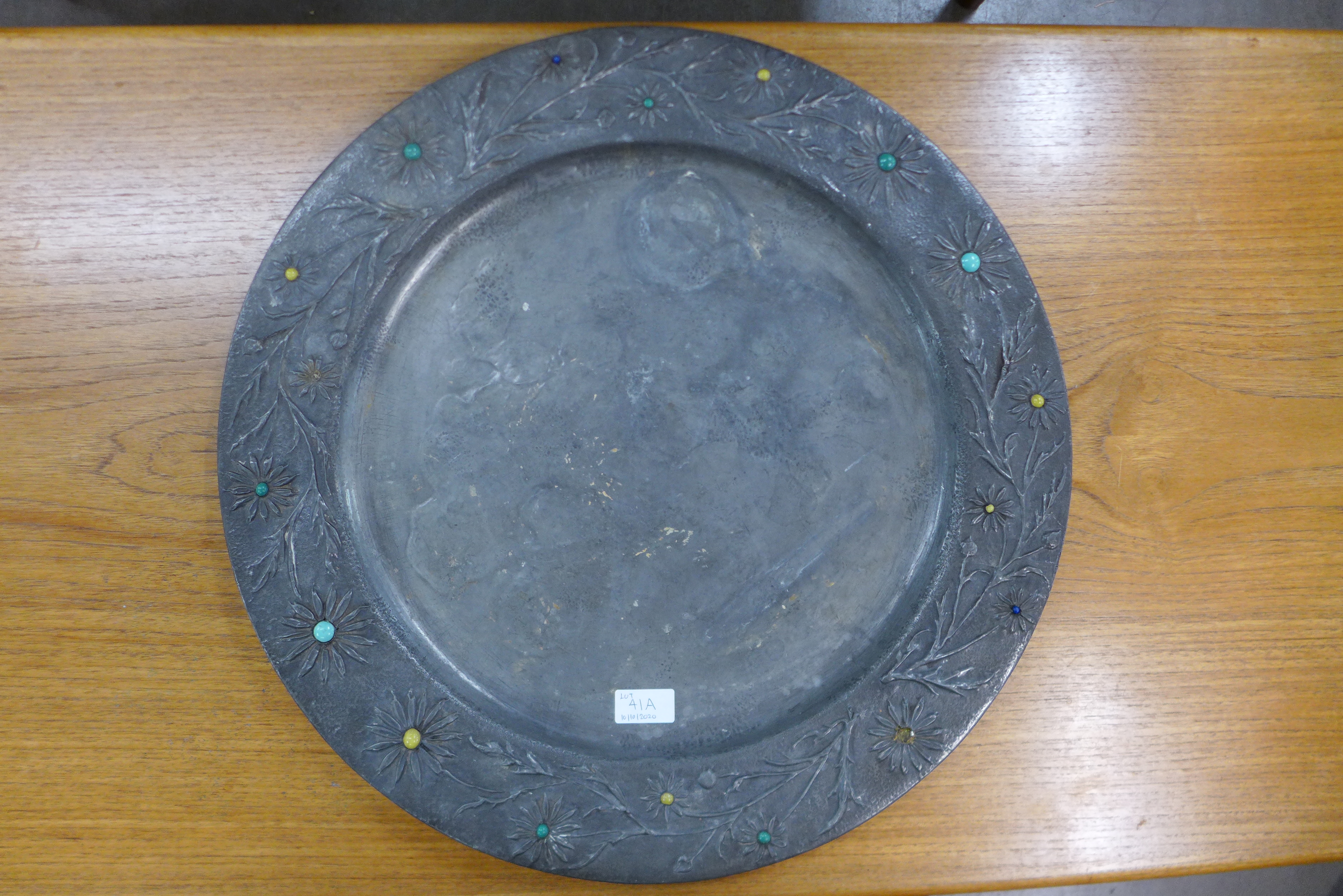 An Arts and Crafts pewter charger, in set with enamelled cabochons