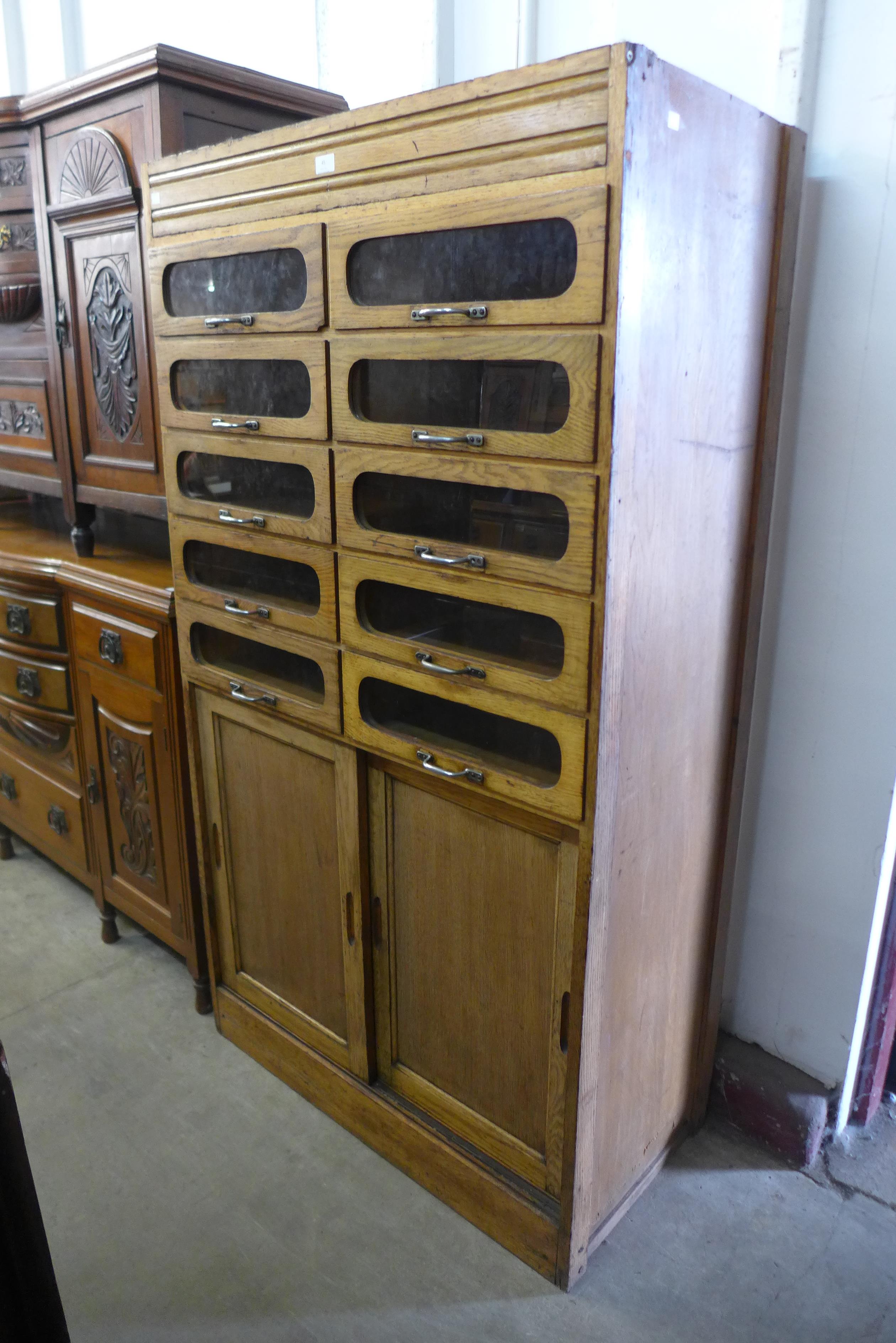 A mid 20th Century oak haberdashery shop cabinet, 172cms h, 94cms w , 48cms d