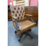 A mahogany and brown leather upholstered revolving desk chair