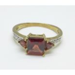 A 9ct gold and red stone ring with diamond shoulders, 2.6g, P