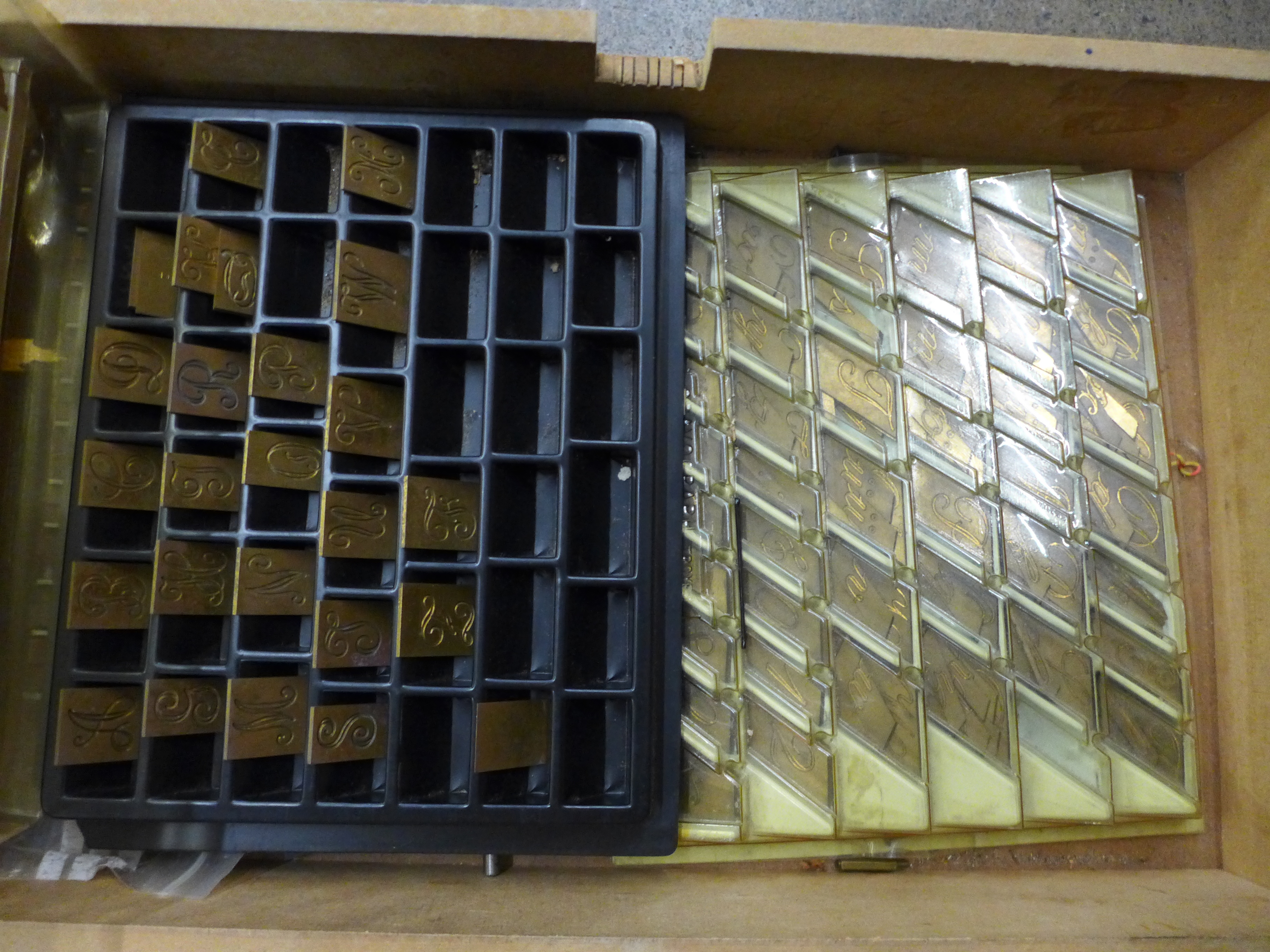 A collection of gravo-graph brass monograms, three trays