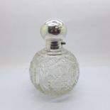 A silver topped globular cut glass scent bottle, the top decorated with a sunrise and two birds,