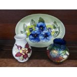 A Moorcroft Pansy pattern oval tray, 23cm wide, an Anna Lily pattern vase and one other Moorcroft