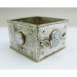 An Arts and Crafts square, hammered white metal napkin holder set with three blister pearls,