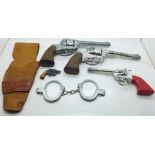 Three cap guns, Lone Star and Crescent Toys, a pair of toy handcuffs and a holster