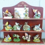 A collection of twelve Danbury Mint bird figures on a display rack