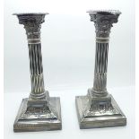 A pair of silver candlesticks of reeded columnar form, with Corinthian tops, each on a square beaded