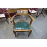 An early 20th Century oak and green leather desk chair