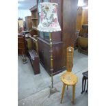 A carved oak spinning stool and a brass standard lamp