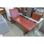 A teak and vinyl examination couch with adjustable headrest