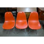 A set of three Eames style red perspex and chrome chairs