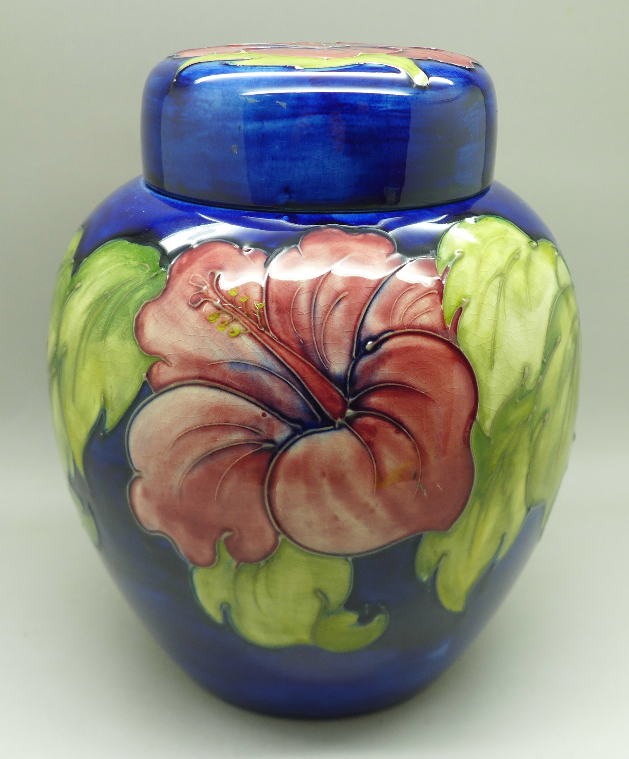 A Moorcroft hibiscus ginger jar on blue ground, signed, with paper label inside lid, 20cm