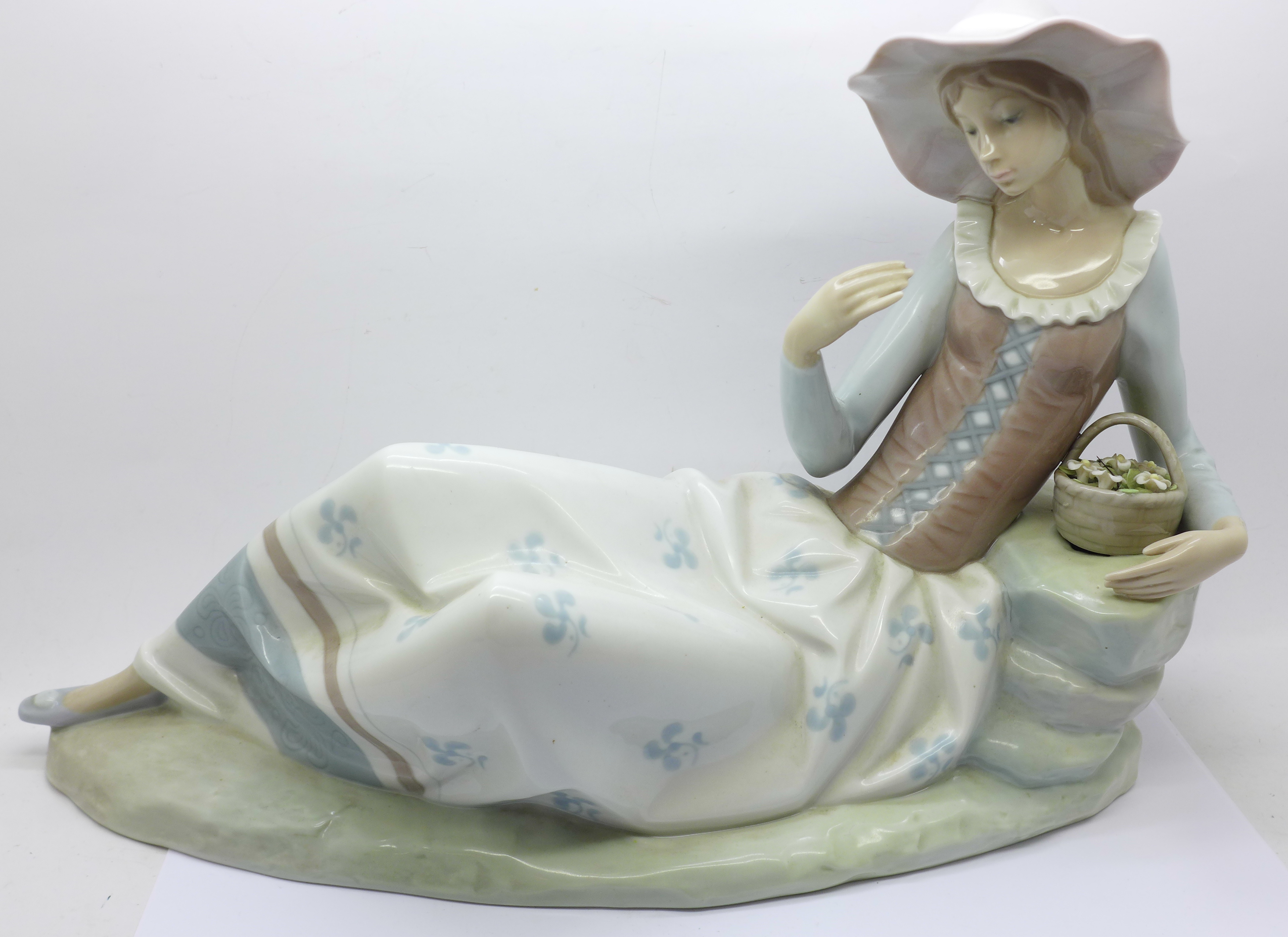 A large Nao figure of a girl reclining, lacking flower from hand