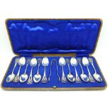 A set of twelve silver tea spoons with a pair of sugar bows, in a fitted case, 131g