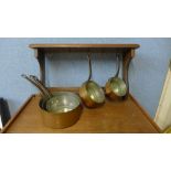 A set of five graduated copper coated saucepans and an oak pan rack