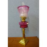 A Victorian brass oil lamp, with cranberry glass reservoir and etched glass shade, converted for