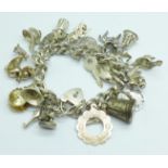 A silver charm bracelet with padlock fastener, each link marked, with twenty-two charms, 92g