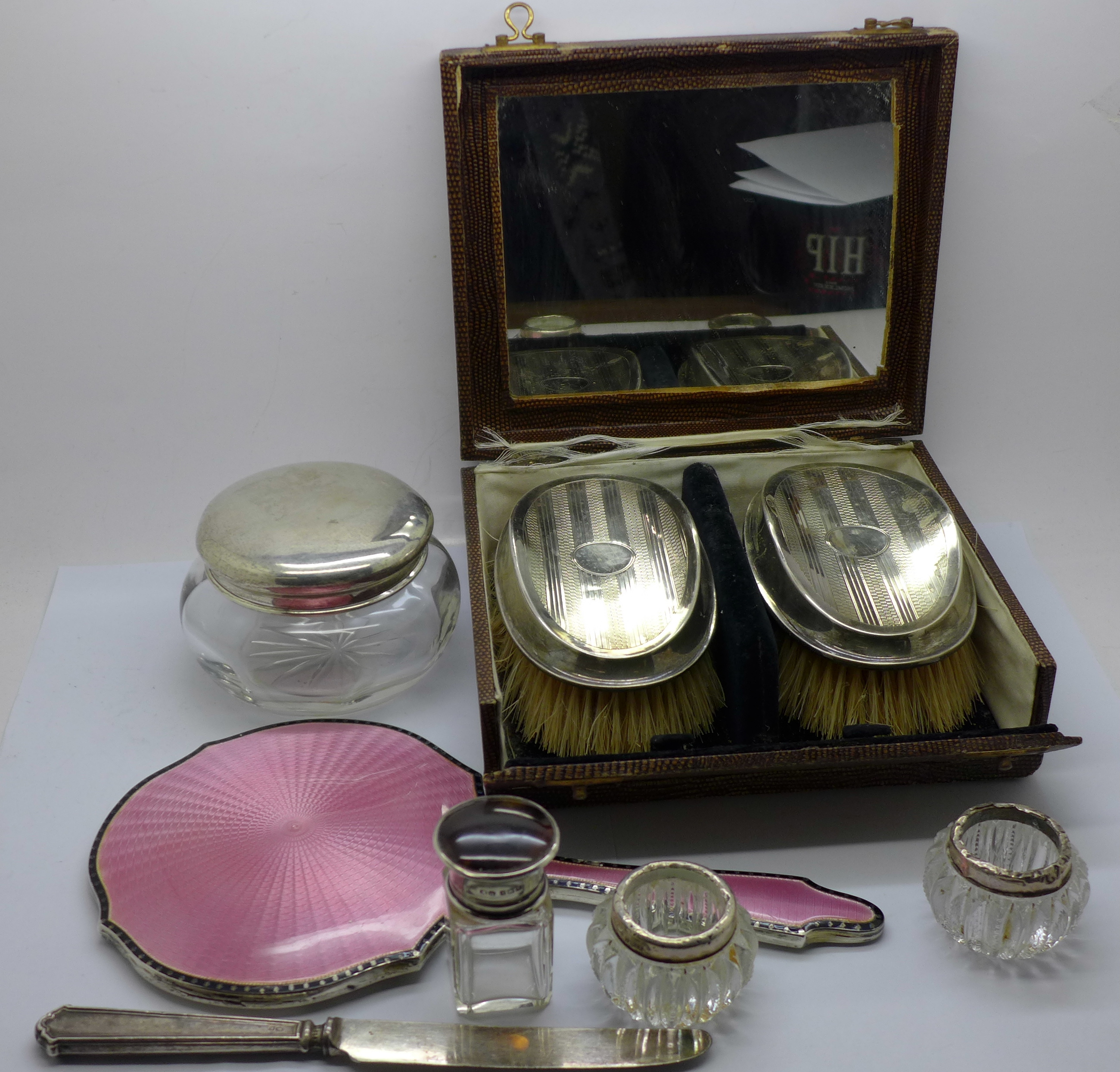 A pair of silver backed brushes, cased, a silver and enamel mirror, a/f, a silver topped glass