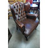 A chestnut brown leather Chesterfield wingback armchair