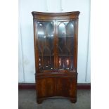 A mahogany freestanding concave corner cabinet