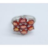 A 9ct white gold, hessonite garnet cluster ring, with diamond shoulders, 3g, K