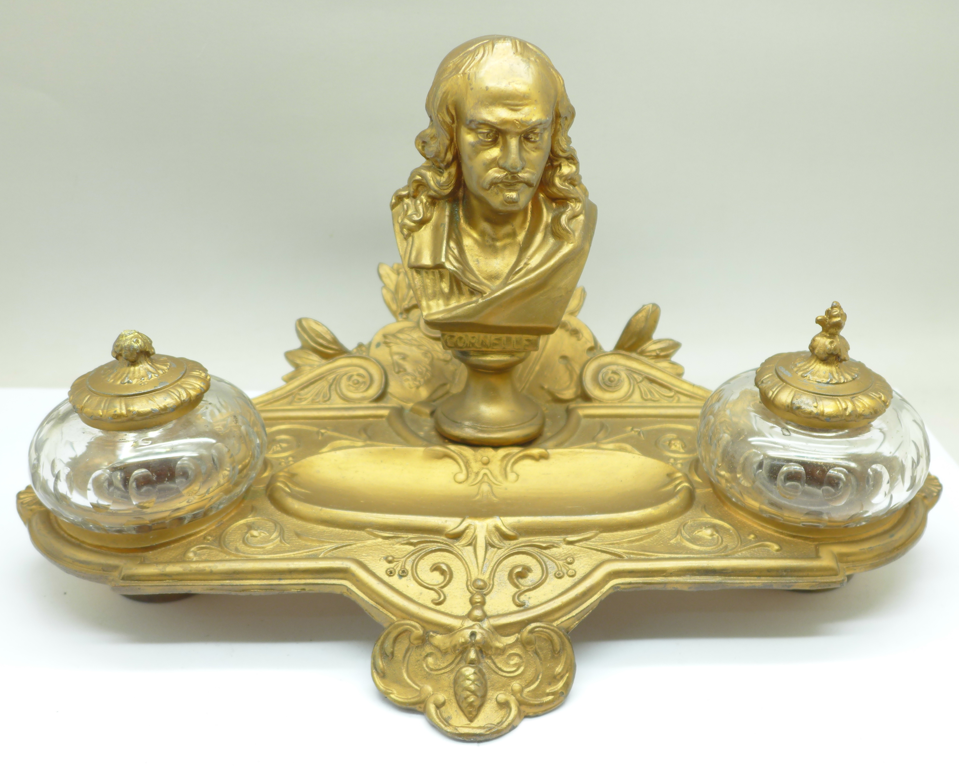 A c.1900 metal inkstand with two glass inkwells, one top a/f, mounted with a bust marked Cornelle