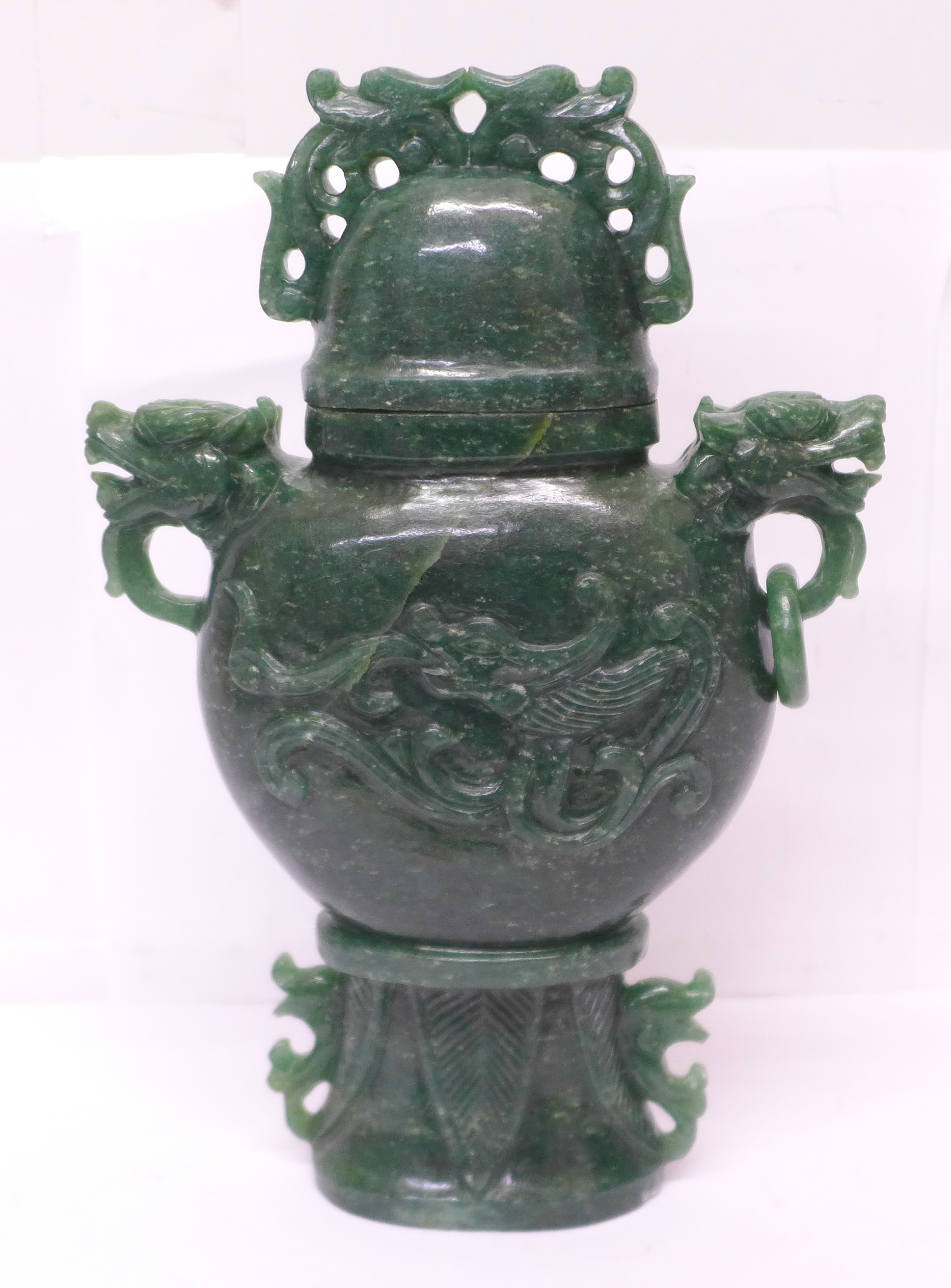 A carved green stone urn with lid, small losses to the lid and one ring missing, 23cm