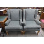 A pair of walnut and upholstered wingback armchairs