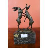 A small French style bronze figure of boxing hares, on black marble socle, 24cms h