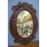 A carved oak oval framed mirror, 72 x 50cms