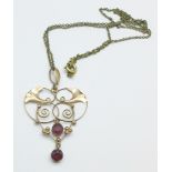 A yellow metal and red stone pendant on a plated chain