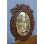 A carved oak oval framed mirror, 72 x 50cms