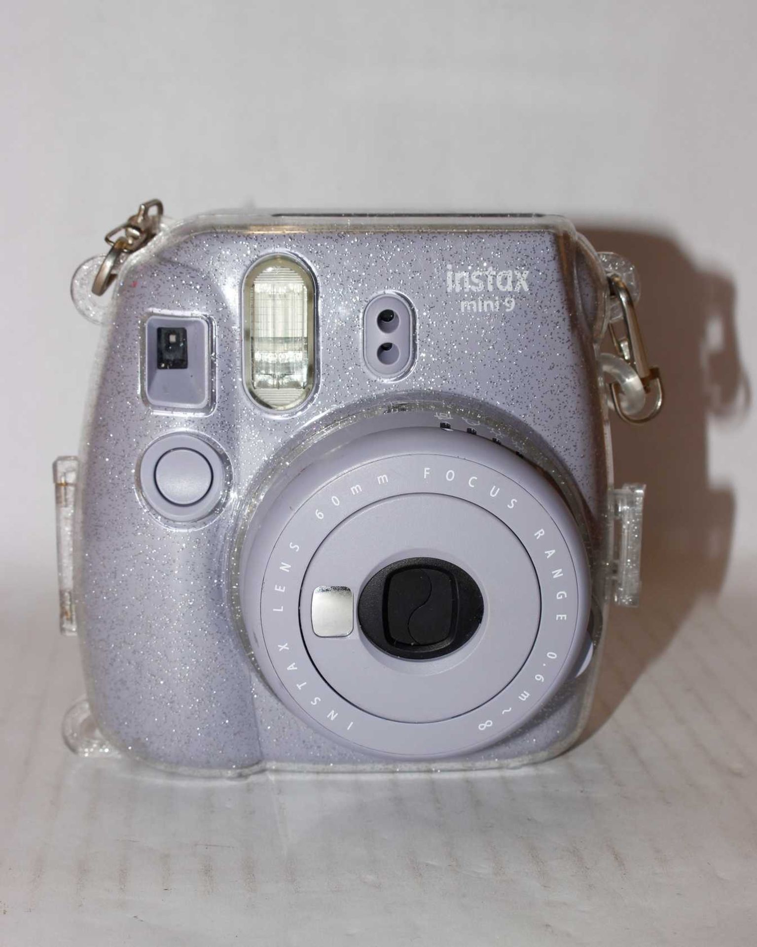 A pre-owned Fujifilm Instax Mini 9 Instant Camera in Lavender with Case in Clear/Glitter.