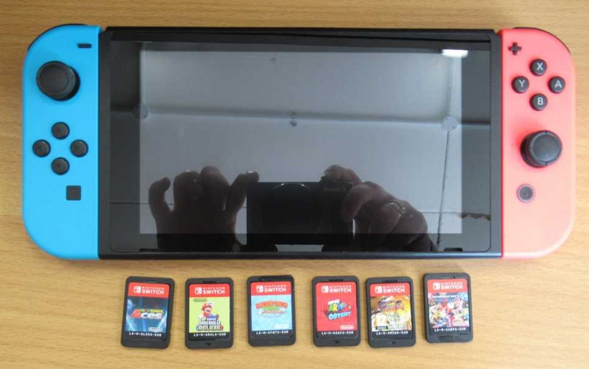 A pre-owned Nintendo Switch Console (HAC-001) with six assorted game cards.