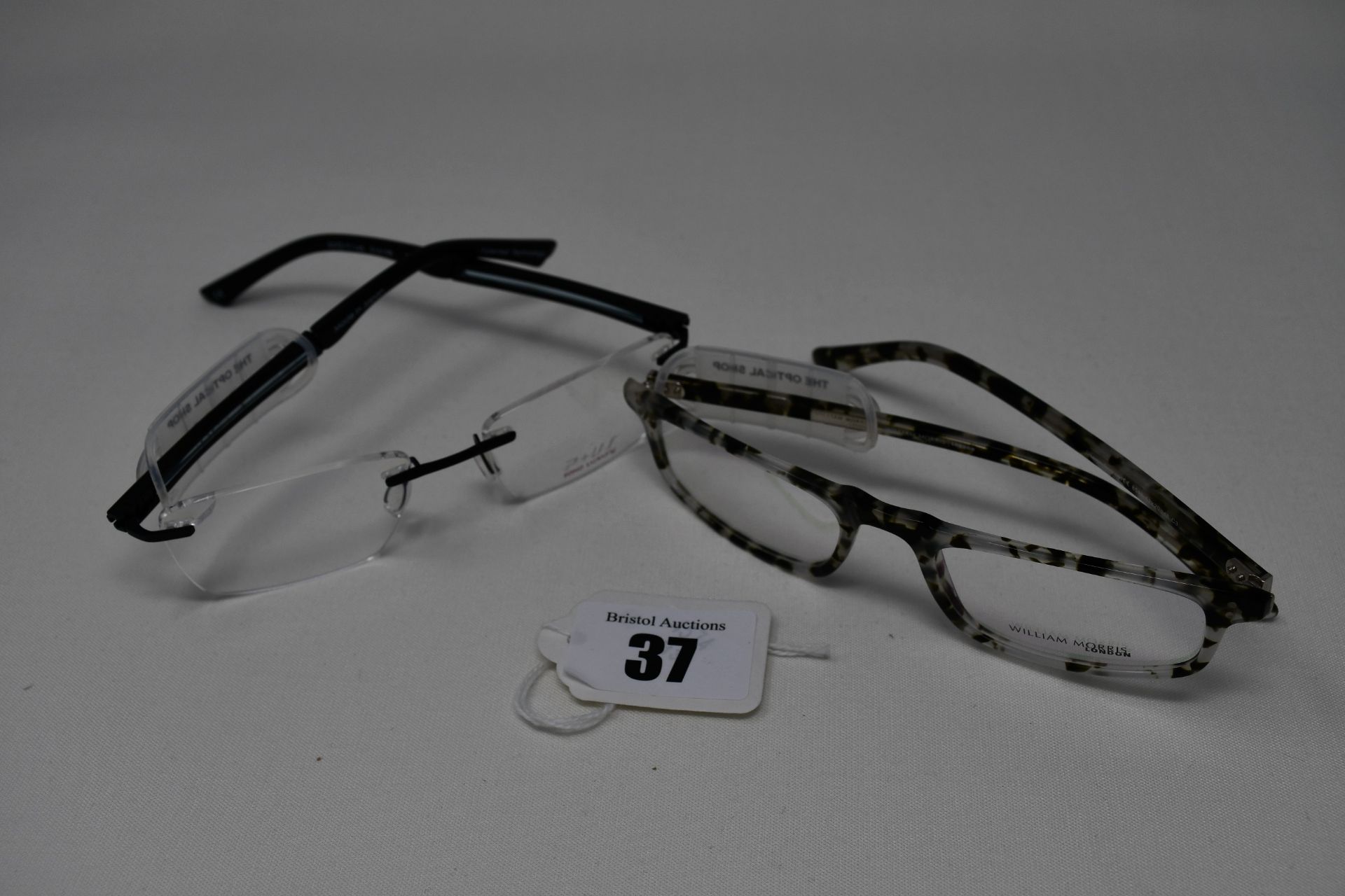 Two pairs of as new glass frames with clear glass; William Morris (RRP £120 ) and P+US (RRP £190).