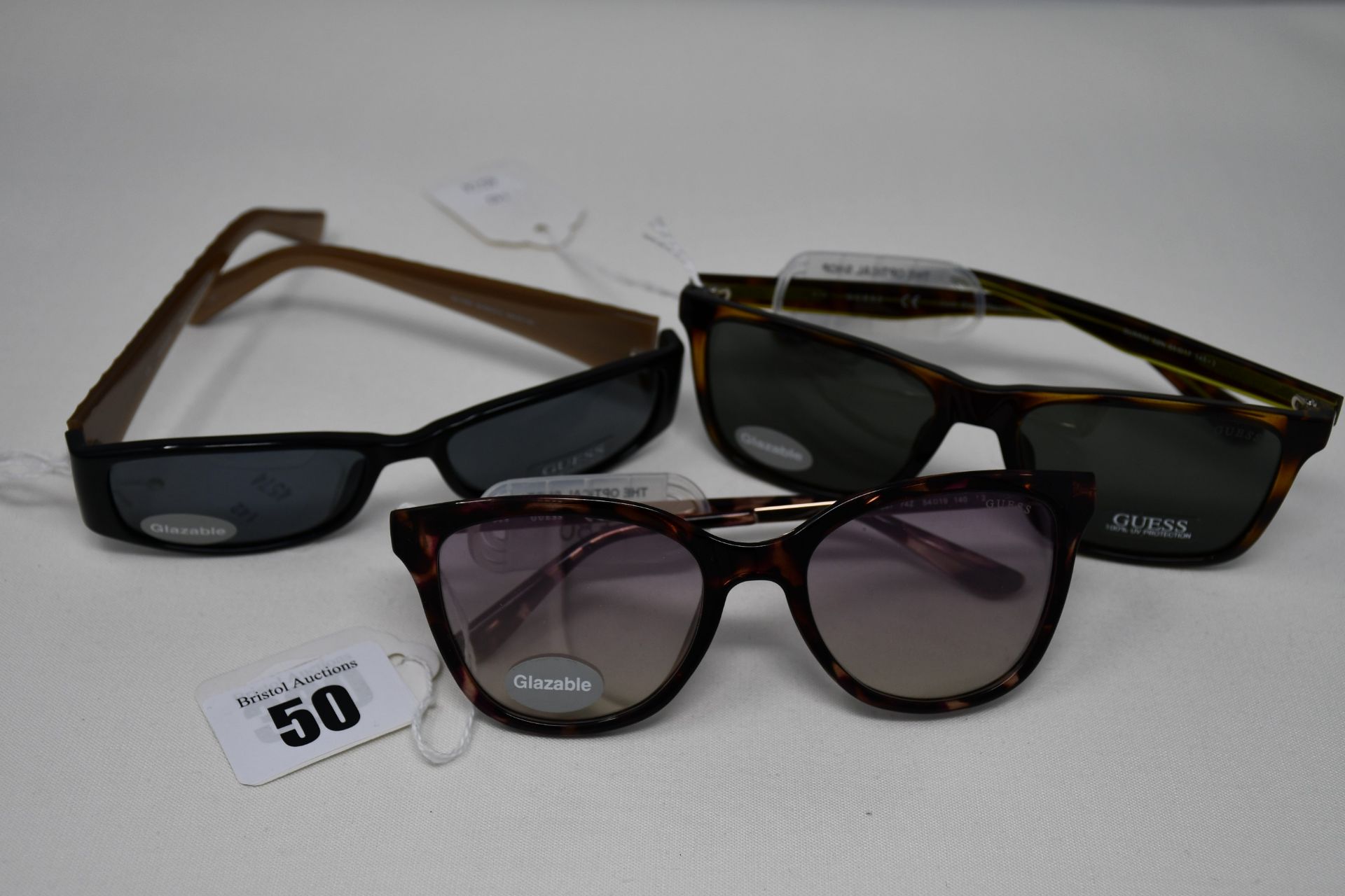 Three pairs of as new Guess sunglasses.