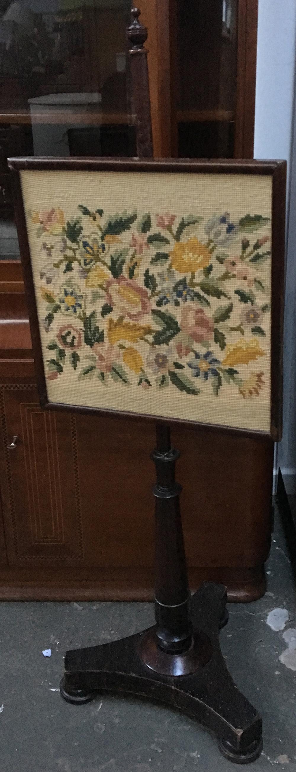 A 19th century embroidered fire screen, on triform base