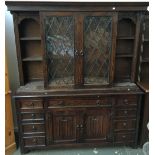 A kitchen dresser with lead glazed central cabinet, sliding to reveal further cupboard, flanked by