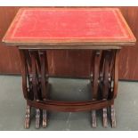 A nest of three tables with lyre supports and tooled leather inset tops