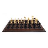 An antique carved ivory and ebony chess set, height of kings 8.1cm, set on wooden stand with cover