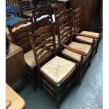 A set of six oak ladderback dining chairs with rush seats (two carvers), the legs joined by turned