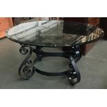 A large circular glass top table on scrolling metal base, 150cmD