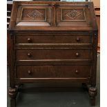 A carved oak bureau, fall front with fitted interior over three shelves, on turned legs on H