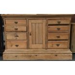 A pine sideboard, having central cupboard door flanked by eight shelves, on pedestal base, 133cmW
